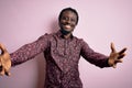Young handsome african american man wearing casual shirt standing over pink background looking at the camera smiling with open Royalty Free Stock Photo