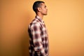 Young handsome african american man wearing casual shirt standing over yellow background looking to side, relax profile pose with Royalty Free Stock Photo