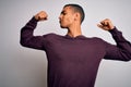 Young handsome african american man wearing casual sweater over white background showing arms muscles smiling proud Royalty Free Stock Photo