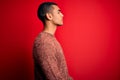 Young handsome african american man wearing casual sweater standing over red background looking to side, relax profile pose with Royalty Free Stock Photo