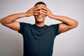 Young handsome african american man wearing casual t-shirt standing over white background covering eyes with hands smiling Royalty Free Stock Photo