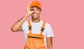 Young handsome african american man wearing handyman uniform doing ok gesture with hand smiling, eye looking through fingers with Royalty Free Stock Photo