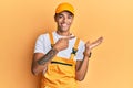 Young handsome african american man wearing handyman uniform over yellow background amazed and smiling to the camera while Royalty Free Stock Photo