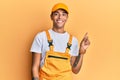 Young handsome african american man wearing handyman uniform over yellow background with a big smile on face, pointing with hand Royalty Free Stock Photo