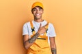 Young handsome african american man wearing handyman uniform over yellow background cheerful with a smile on face pointing with Royalty Free Stock Photo