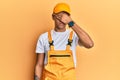 Young handsome african american man wearing handyman uniform over yellow background covering eyes with hand, looking serious and