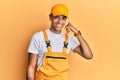 Young handsome african american man wearing handyman uniform over yellow background smiling doing phone gesture with hand and Royalty Free Stock Photo