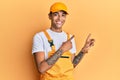 Young handsome african american man wearing handyman uniform over yellow background smiling and looking at the camera pointing Royalty Free Stock Photo