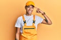 Young handsome african american man wearing handyman uniform over yellow background smiling pointing to head with one finger, Royalty Free Stock Photo