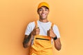 Young handsome african american man wearing handyman uniform over yellow background success sign doing positive gesture with hand, Royalty Free Stock Photo