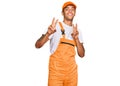 Young handsome african american man wearing handyman uniform smiling looking to the camera showing fingers doing victory sign Royalty Free Stock Photo