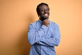 Young handsome african american man wearing shirt and glasses over yellow background looking confident at the camera smiling with Royalty Free Stock Photo