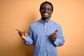 Young handsome african american man wearing shirt and glasses over yellow background smiling confident pointing with fingers to Royalty Free Stock Photo