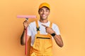 Young handsome african american man window cleaner holding glass washer smiling happy pointing with hand and finger Royalty Free Stock Photo