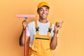 Young handsome african american man window cleaner holding glass washer smiling happy pointing with hand and finger to the side Royalty Free Stock Photo