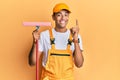 Young handsome african american man window cleaner holding glass washer smiling with an idea or question pointing finger with Royalty Free Stock Photo