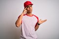 Young handsome african american sportsman wearing striped baseball t-shirt and cap confused and annoyed with open palm showing