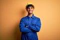 Young handsome african american worker man wearing blue uniform and security helmet happy face smiling with crossed arms looking Royalty Free Stock Photo