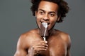 Young handsome african man eating icecream over grey background. Royalty Free Stock Photo