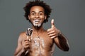 Young handsome african man eating icecream over grey background. Royalty Free Stock Photo