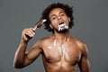 Young handsome african man eating icecream over grey background. Royalty Free Stock Photo