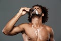 Young handsome african man eating icecream over grey background. Royalty Free Stock Photo