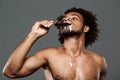 Young handsome african man eating icecream over grey background. Royalty Free Stock Photo