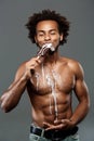 Young handsome african man eating icecream over grey background. Royalty Free Stock Photo