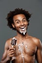 Young handsome african man eating icecream over grey background. Royalty Free Stock Photo