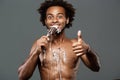 Young handsome african man eating icecream over grey background. Royalty Free Stock Photo