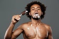 Young handsome african man eating icecream over grey background. Royalty Free Stock Photo