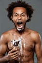 Young handsome african man eating icecream over grey background. Royalty Free Stock Photo