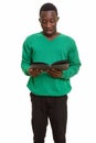 Young handsome African man looking shocked while reading book