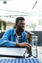 Young handsome african man talk phone on loudspeaker in cafe Royalty Free Stock Photo