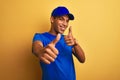 Young handsome arab delivery man standing over isolated yellow background approving doing positive gesture with hand, thumbs up Royalty Free Stock Photo