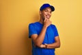 Young handsome arab delivery man standing over isolated yellow background looking confident at the camera smiling with crossed Royalty Free Stock Photo