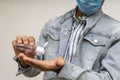 Young handsome asian boy in denims wearing a mask using a hand sanitizer