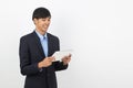 Young handsome asian business man playing and looking to tablet computer with smiling isolated on white background. Royalty Free Stock Photo