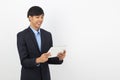 Young handsome asian business man playing and looking to tablet computer with smiling isolated on white background. Royalty Free Stock Photo