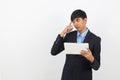 Young handsome asian business man using tablet computer with doubts isolated on white background. Royalty Free Stock Photo