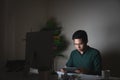 Young handsome asian business thoughtful man thinking, holding and looking tablet sitting at desk work late night at home with Royalty Free Stock Photo