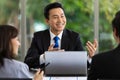 Young handsome asian businessman smiling and talking to his team during a discussion about company business in the office. Royalty Free Stock Photo