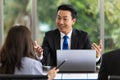 Young handsome asian businessman smiling and talking to his team during a discussion about company business in the office. Royalty Free Stock Photo