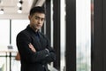 Young handsome asian businessman in suit standing near window with arm crossed in office Royalty Free Stock Photo