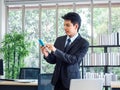 Young handsome Asian businessman in suit using mobile phone in office Royalty Free Stock Photo