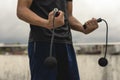 A young handsome asian man holding a cordless jumping ropes outside a floor deck. Cardio training exercise regimen