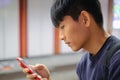 Young handsome asian man looking at cellphone checking social media, surfing internet, ordering food delivery, using mobile apps