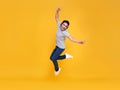 Young handsome Asian man smiling and jumping wearing wireless headphone listening to music isolated over yellow background Royalty Free Stock Photo