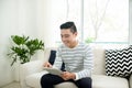 Young handsome asian man using digital tablet sitting on a couch Royalty Free Stock Photo