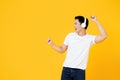 Young Asian man wearing headphones listening to music and dancing on yellow background Royalty Free Stock Photo